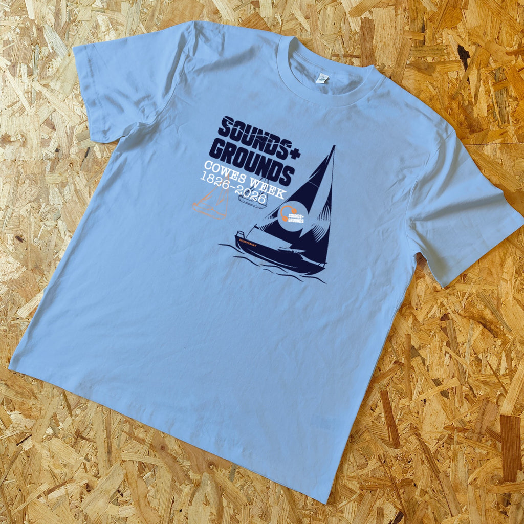 Light blue t-shirt with sailboat graphic and text on a wooden surface