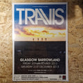 Travis concert poster on a wooden surface